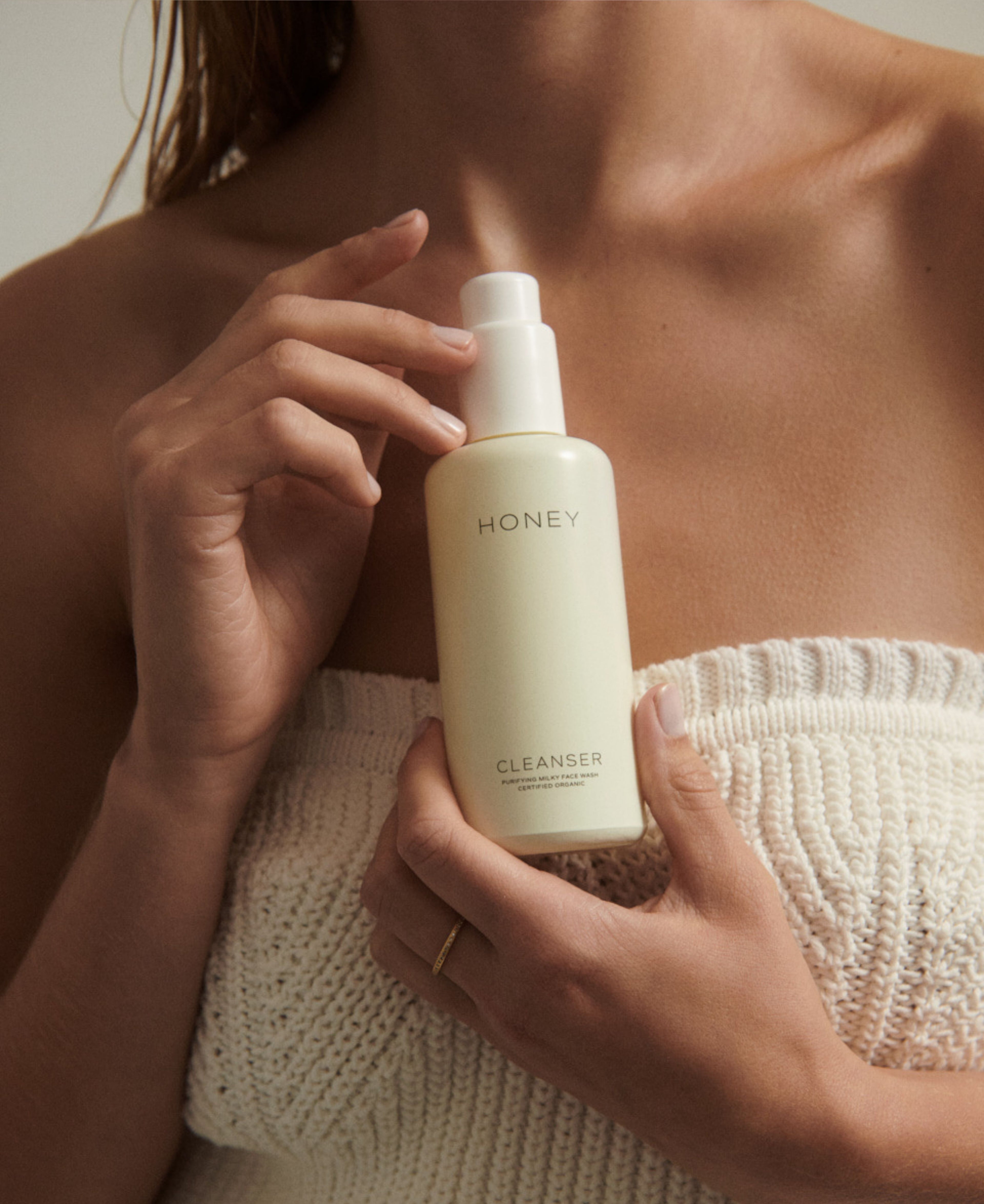 Kvinde med naturlig ren cleanser - ansigtsvask i lysegul flaske med hvid låg