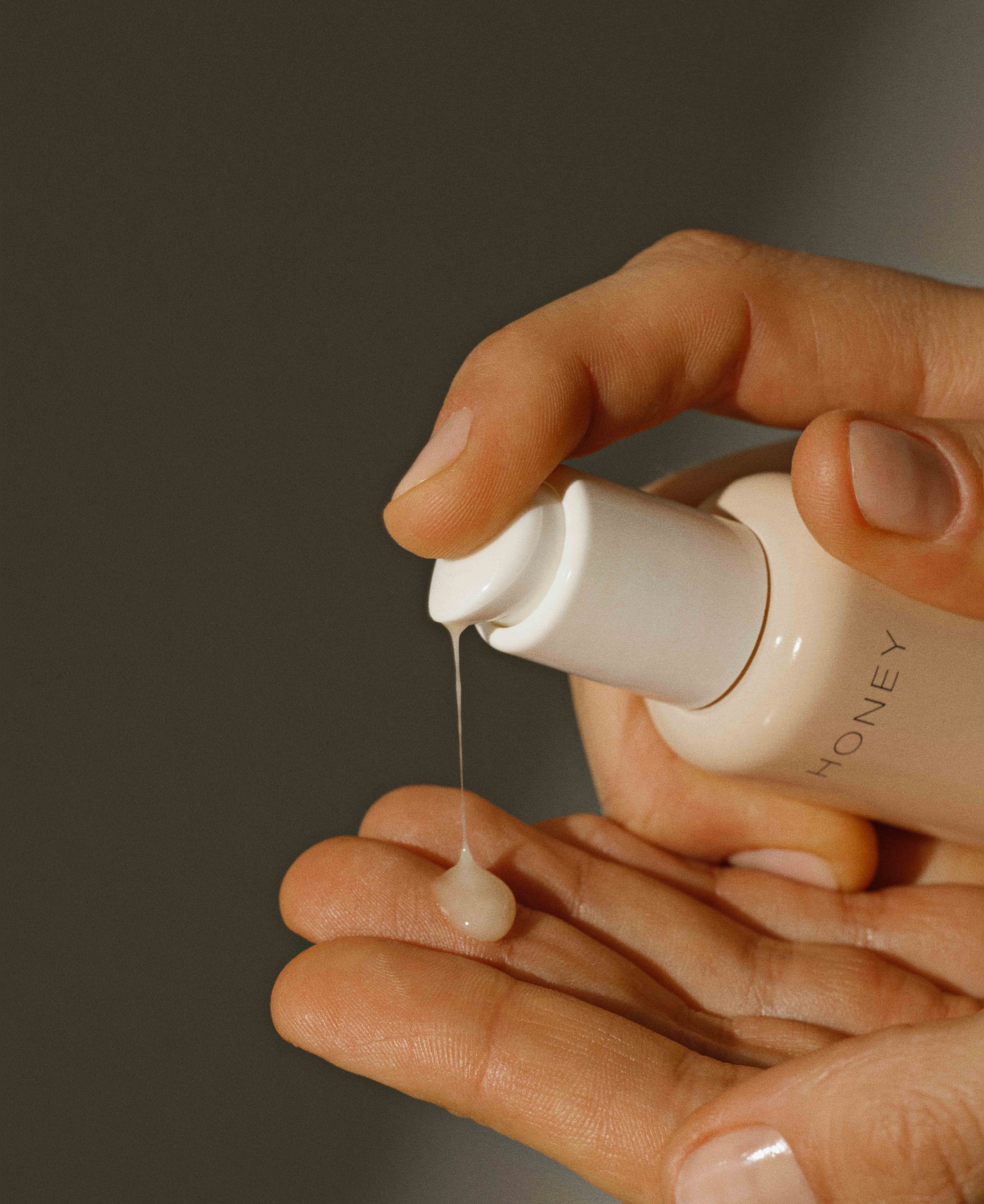 Hånd hældende naturligt hydra-serum fra støvet pink flaske med hvid låg - parfumefri hudpleje