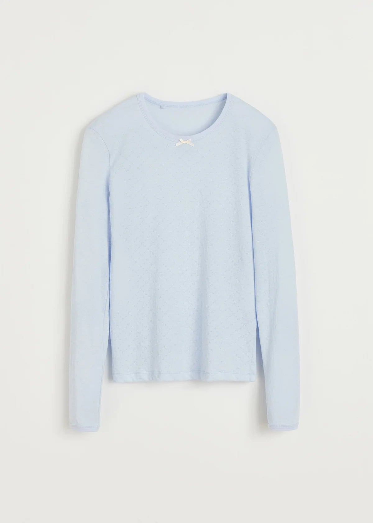 Produktfoto af langærmet lyseblå bluse med sløjfe og hulmønster.