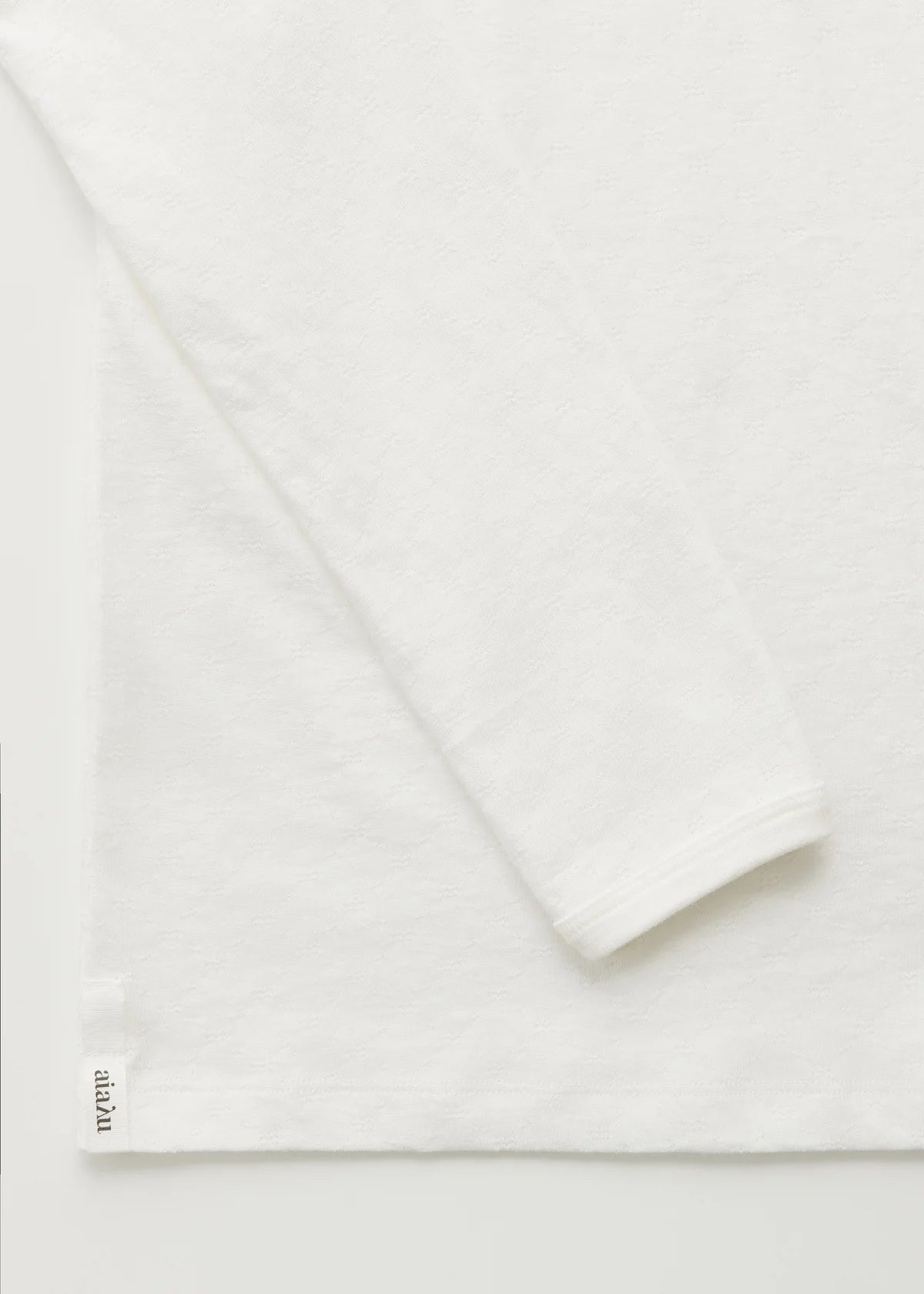 Detaljer af ærme og hjørne ad hvid bluse i pointelle.