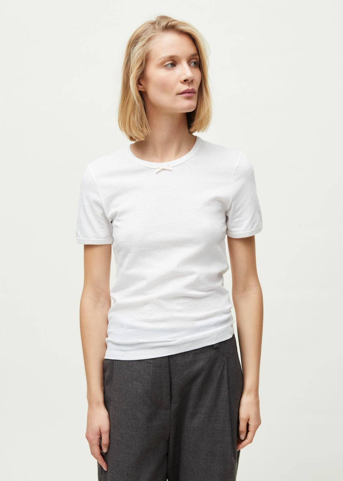 Kvinde i kortærmet hvid bomulds t-shirt med sløjfe fra Aiayu og grå bukser