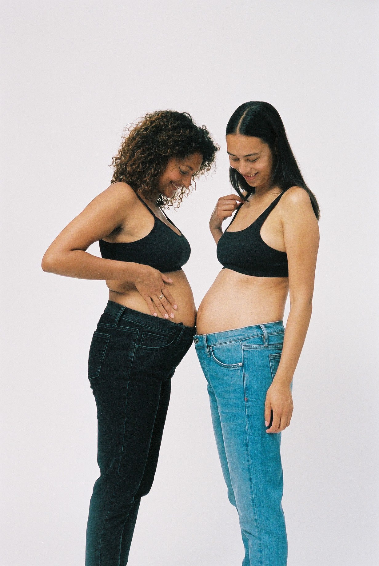 To kvinder iført blå og sorte graviditetsjeans og bh