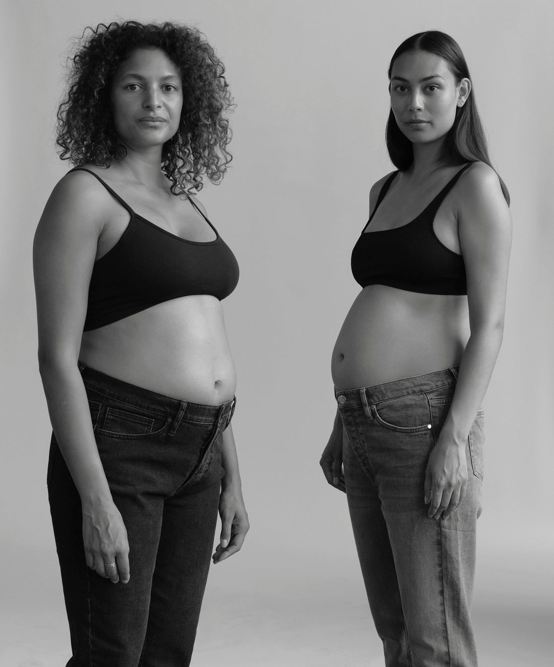 To kvinder iført blå og sorte graviditetsjeans og bh