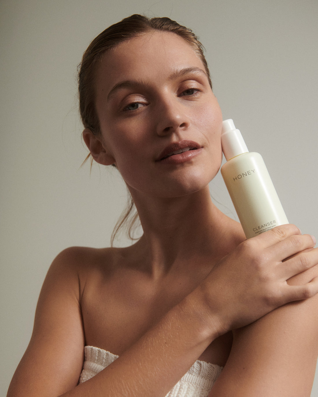 Kvinde med naturlig ren cleanser - ansigtsvask i lysegul flaske med hvid låg